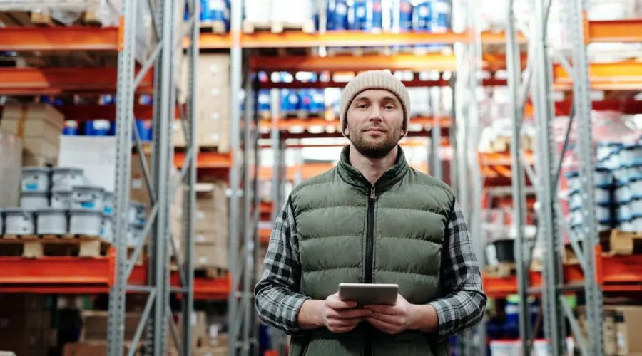 A warehouse worker using a tablet between storage racks