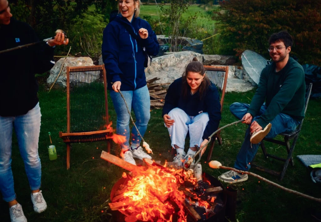how.fm colleagues around a campfire at a summer party